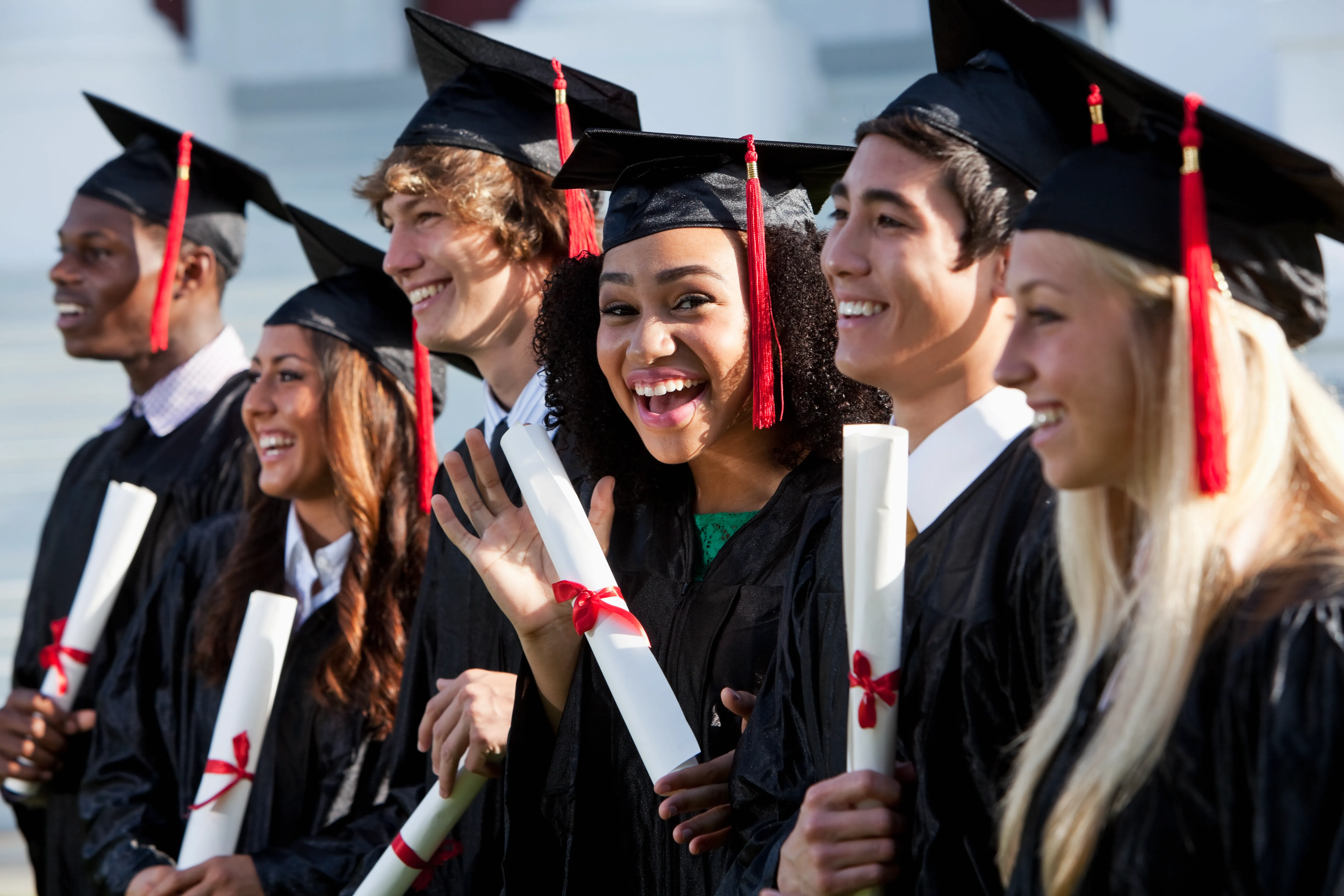Stock image of graduates in caps and gowns holding diplomas